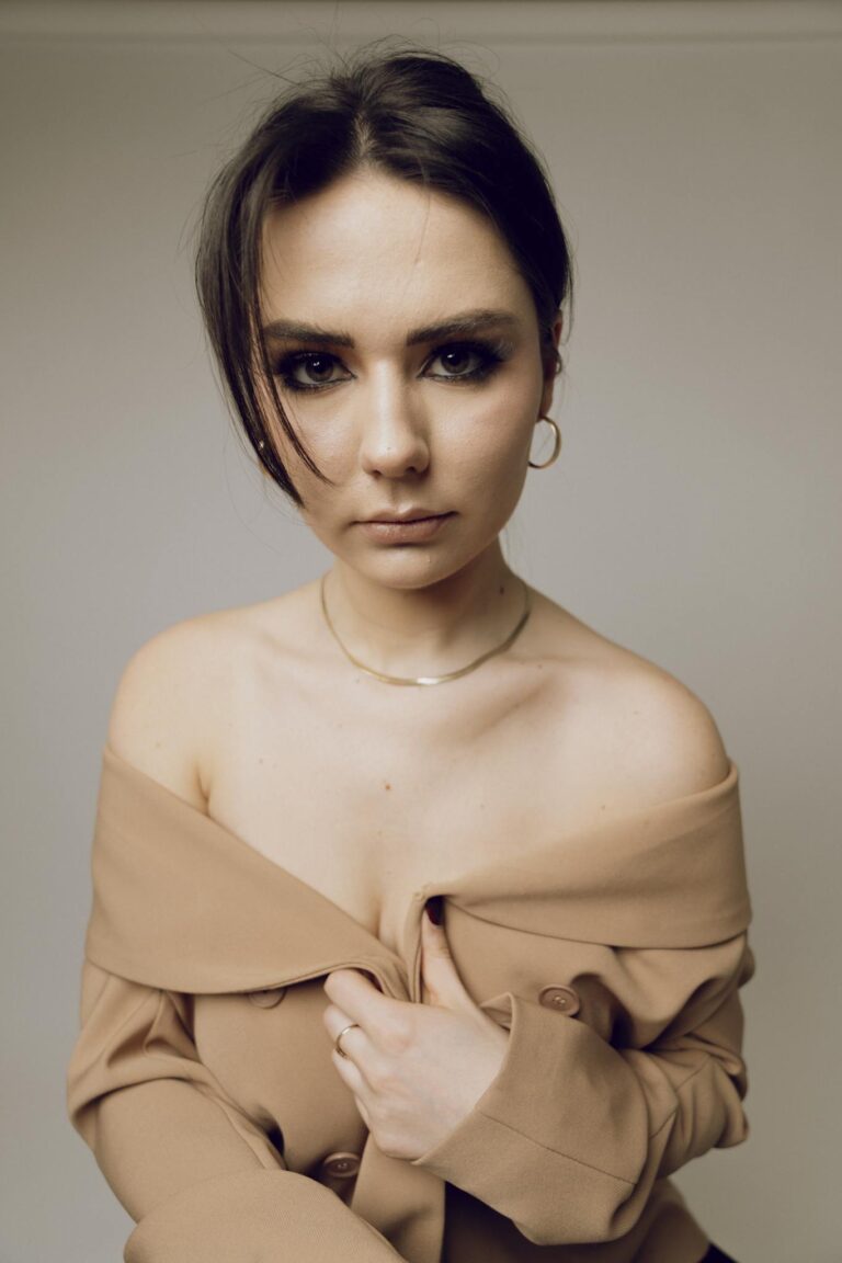Striking indoor portrait of a woman in a beige jacket, captured in a studio setting.