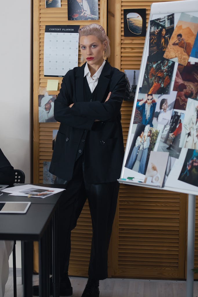 Confident woman in black blazer presenting a fashion mood board during a creative meeting.